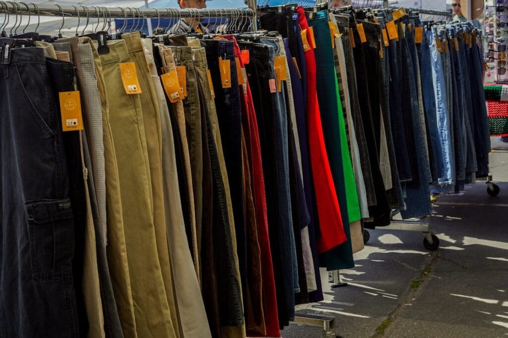 Row of pants on hangers at a garage sale. 