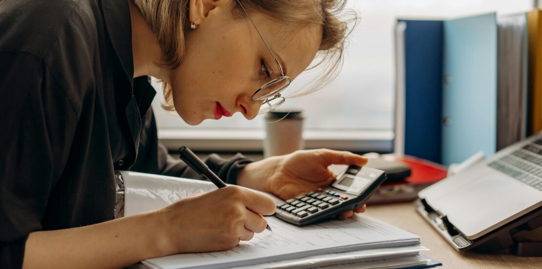 Young professional calculating assets with a calculator and notes.