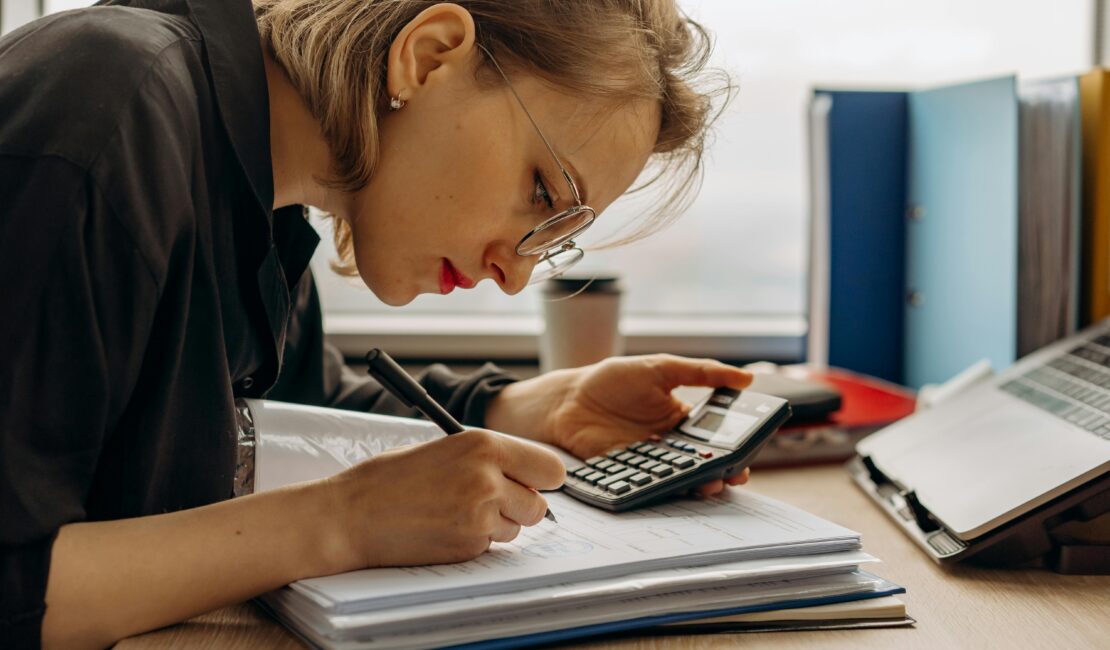 Young professional calculating assets with a calculator and notes.
