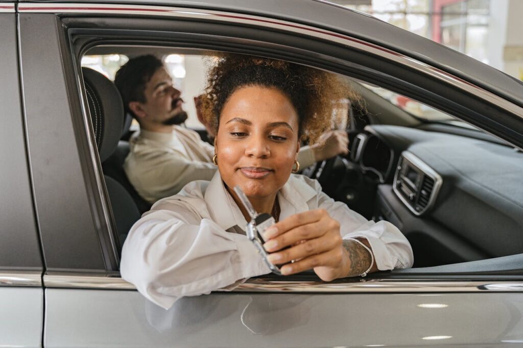 Woman sitting in a car holding keys, symbolizing the decision between leasing and owning a vehicle.
